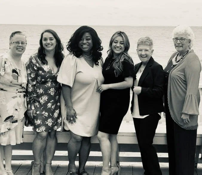 The image shows a group of people posing together for a photograph at an event, with some individuals smiling towards the camera.