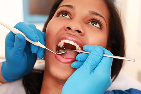 A woman receiving dental treatment with a hygienist performing a cleaning procedure.